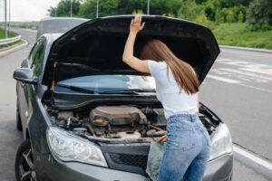 Mujer junto a carro averiado